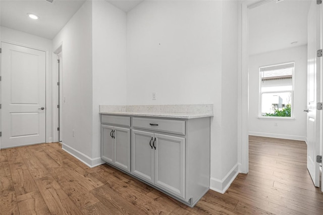 corridor featuring recessed lighting, light wood-type flooring, and baseboards