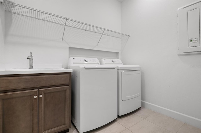 laundry room with light tile patterned floors, separate washer and dryer, a sink, baseboards, and cabinet space