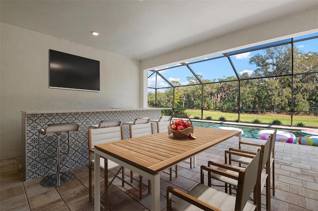 dining space with recessed lighting, a sunroom, and a textured wall