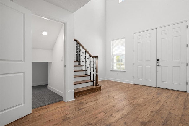 entryway with wood finished floors, baseboards, and stairs