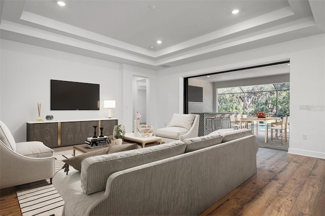 living room with a tray ceiling, baseboards, recessed lighting, and hardwood / wood-style flooring