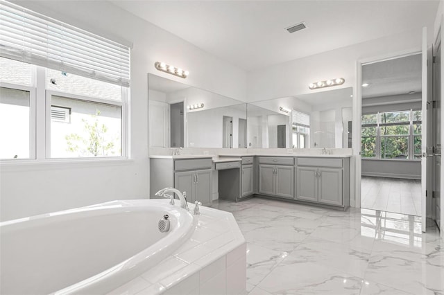 full bath featuring visible vents, a sink, marble finish floor, a garden tub, and two vanities