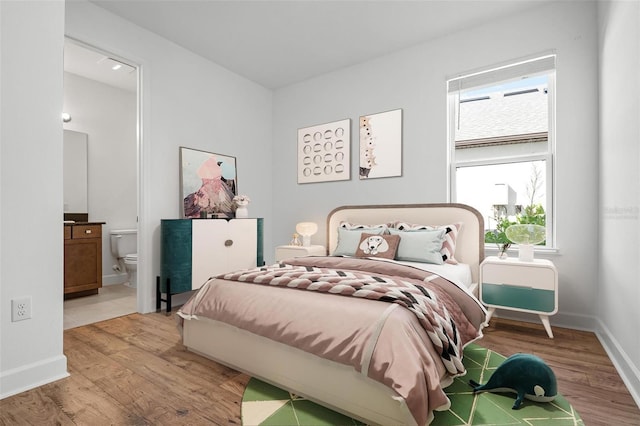 bedroom featuring baseboards, connected bathroom, and light wood-style floors