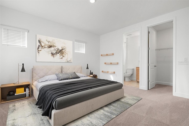 carpeted bedroom with baseboards, a walk in closet, and connected bathroom