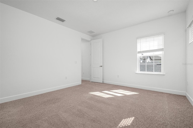 carpeted spare room featuring visible vents and baseboards