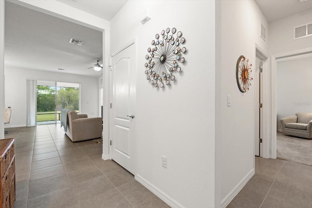 hallway with baseboards, visible vents, and tile patterned floors