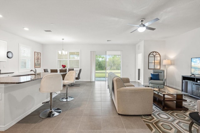 living area with ceiling fan with notable chandelier, tile patterned flooring, visible vents, and baseboards