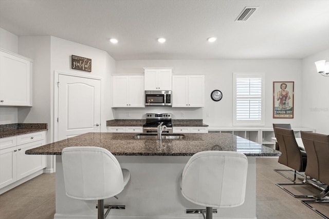 kitchen with visible vents, stainless steel appliances, a kitchen bar, a sink, and light tile patterned flooring