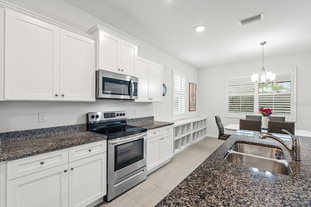 kitchen featuring stainless steel appliances, visible vents, white cabinets, a sink, and a chandelier