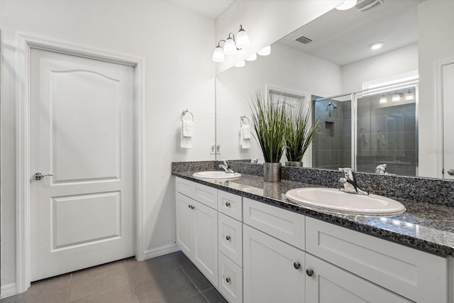 bathroom featuring double vanity, a stall shower, a sink, and tile patterned floors