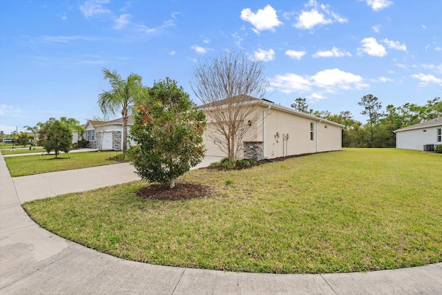 view of home's exterior with a garage, concrete driveway, a yard, and stucco siding