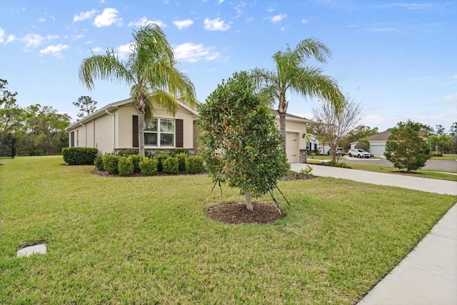 view of front of house with a front yard, driveway, an attached garage, and stucco siding