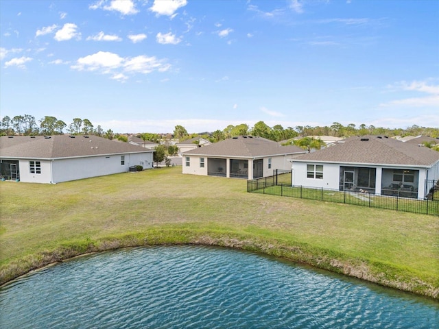 exterior space featuring a water view, a sunroom, a fenced backyard, and a lawn