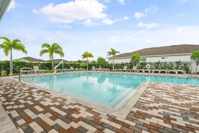 community pool with a patio and fence