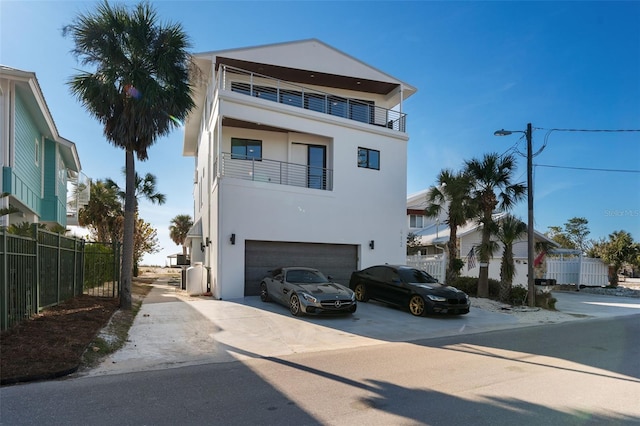 view of front of house featuring driveway, fence, an attached garage, and stucco siding