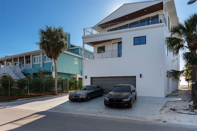 view of building exterior with concrete driveway, fence, and an attached garage