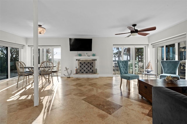 living room with a ceiling fan and a fireplace with raised hearth