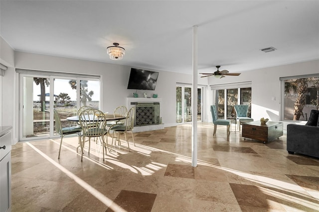 dining room with a fireplace with raised hearth, plenty of natural light, and visible vents