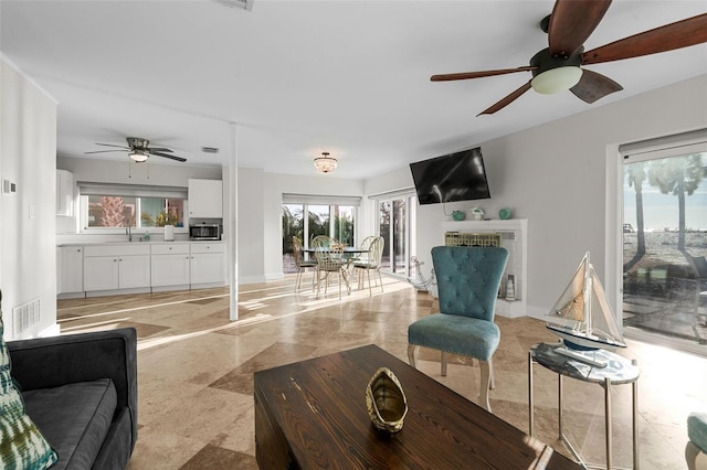 living area featuring ceiling fan, visible vents, and baseboards