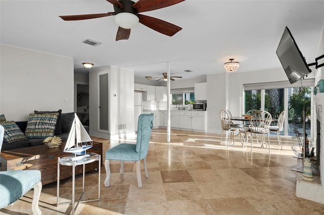 living area featuring baseboards, visible vents, and a ceiling fan