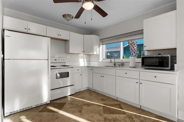 kitchen featuring white appliances, white cabinets, a ceiling fan, crown molding, and a sink