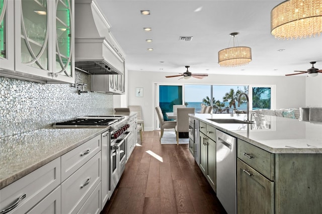 kitchen featuring dark wood-style floors, custom range hood, decorative backsplash, appliances with stainless steel finishes, and a sink