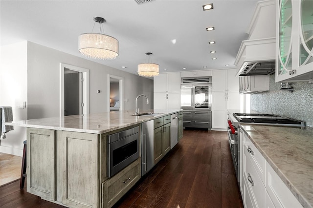 kitchen featuring built in appliances, dark wood-type flooring, a sink, and decorative backsplash