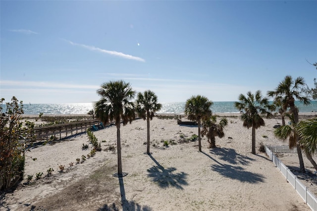 exterior space with a water view, fence, and a beach view