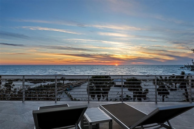 patio terrace at dusk with a balcony and a water view