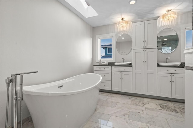 bathroom with a skylight, marble finish floor, a soaking tub, and vanity