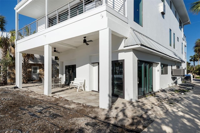 rear view of house with ceiling fan, a patio, and stucco siding