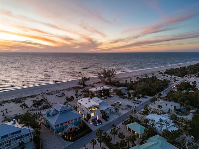 aerial view at dusk with a view of the beach and a water view