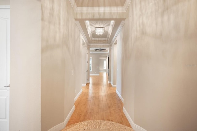 corridor featuring baseboards, light wood-type flooring, and ornamental molding