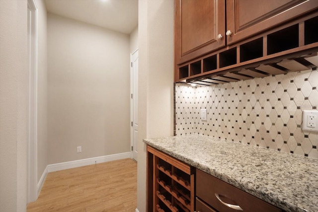 bar featuring backsplash, baseboards, wine cooler, light wood-style floors, and a bar