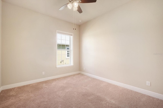 spare room with light colored carpet, baseboards, and ceiling fan