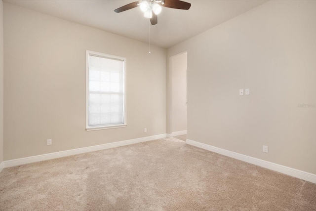 spare room with a ceiling fan, baseboards, and light carpet