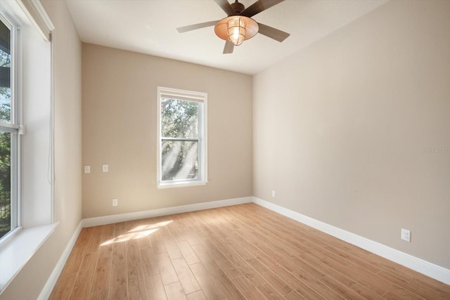 empty room with a ceiling fan, light wood-style floors, and baseboards