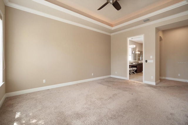 spare room with visible vents, baseboards, light colored carpet, arched walkways, and a raised ceiling