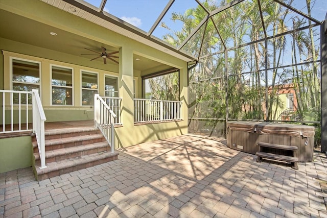 view of patio / terrace with glass enclosure, a hot tub, and ceiling fan