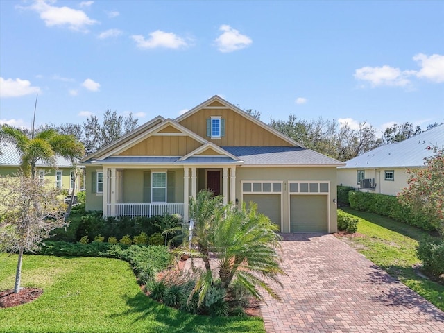 view of front facade featuring a porch, a front yard, decorative driveway, and a garage