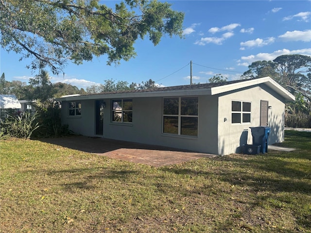 back of house with a lawn, a patio area, and stucco siding