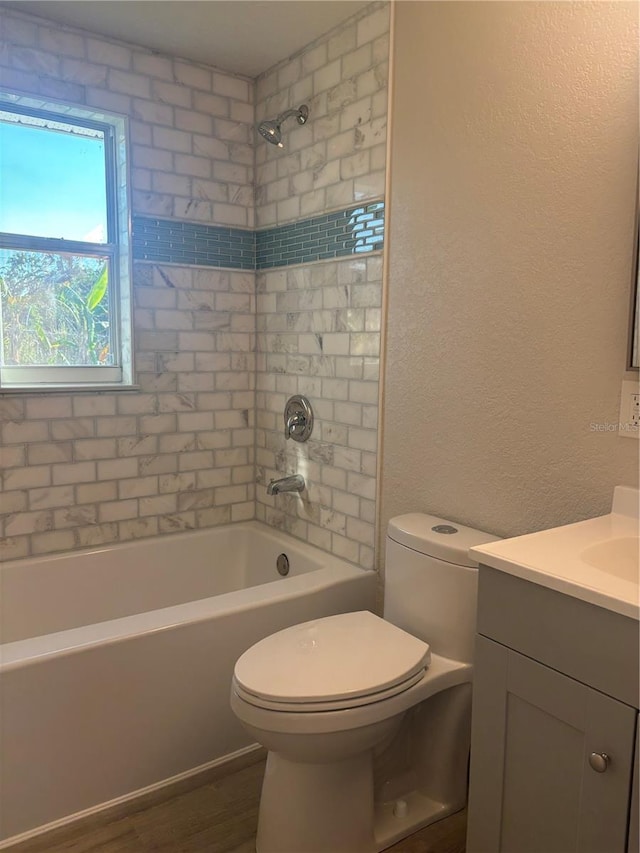 full bathroom with a textured wall, toilet, wood finished floors, bathing tub / shower combination, and vanity