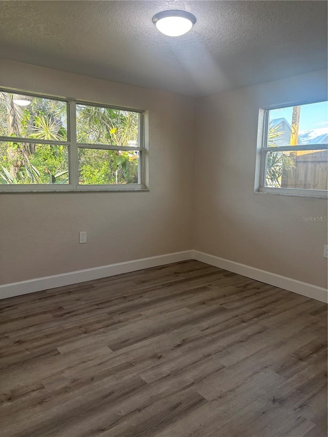 unfurnished room featuring a textured ceiling, baseboards, and wood finished floors