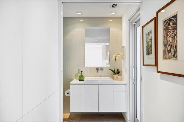 bathroom featuring tile walls, visible vents, vanity, and tasteful backsplash