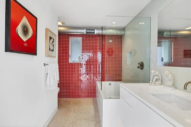 bathroom with vanity, a bathing tub, tiled shower, and tile walls