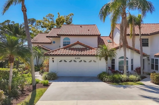 mediterranean / spanish house featuring a garage, concrete driveway, a tile roof, and stucco siding