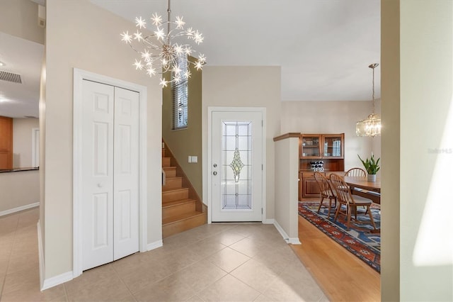 foyer featuring a chandelier, visible vents, baseboards, stairs, and tile patterned floors