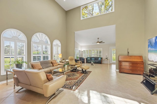 living room featuring light tile patterned floors, baseboards, a towering ceiling, and a healthy amount of sunlight