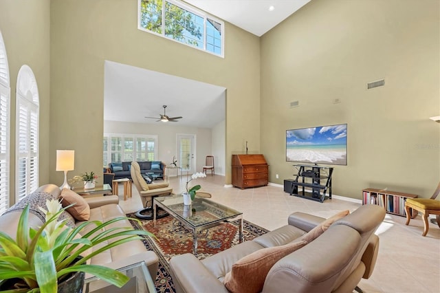 living room with light tile patterned floors, ceiling fan, a high ceiling, visible vents, and baseboards