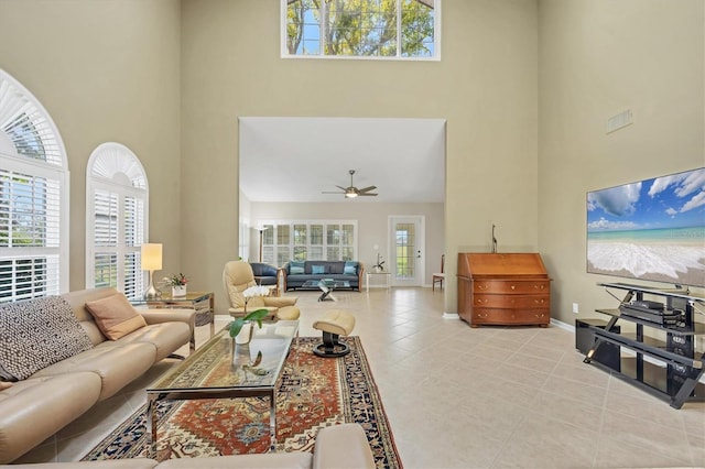 tiled living room featuring baseboards, a healthy amount of sunlight, visible vents, and a high ceiling